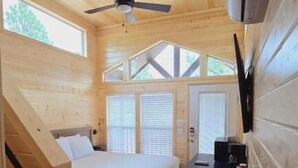 Une cabine équipée d’un lit, d’un bureau, d’un ventilateur de plafond et d’une fenêtre.
