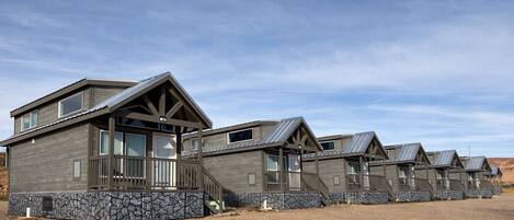 A row of cabins with stone foundations, wooden exteriors, and metal roofs.