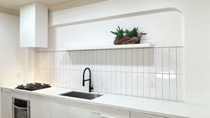 A modern kitchen with white cabinetry, a stainless steel sink, and a built-in stove. - masterfully blend modern luxury studio with thoughtful details (Los Angeles)