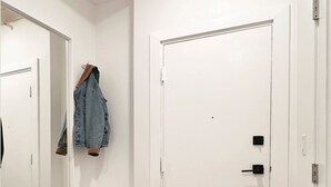 A white door with a black handle, a mirror, and a hanging denim jacket. - masterfully blend modern luxury studio with thoughtful details (Los Angeles)