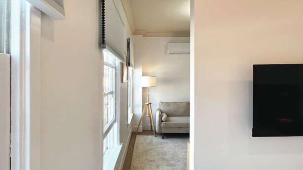 A narrow hallway with a bed on the right, a sofa in the background, and a lamp. - masterfully blend modern luxury studio with thoughtful details (Los Angeles)