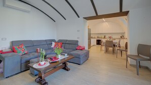 A modern living room with a grey sofa, a wooden coffee table, and a dining area with a kitchen in the background. - Peschiera few steps from the lake Garden, Terrace, & AC, Peschiera del Garda, Italy (Peschiera del Garda)