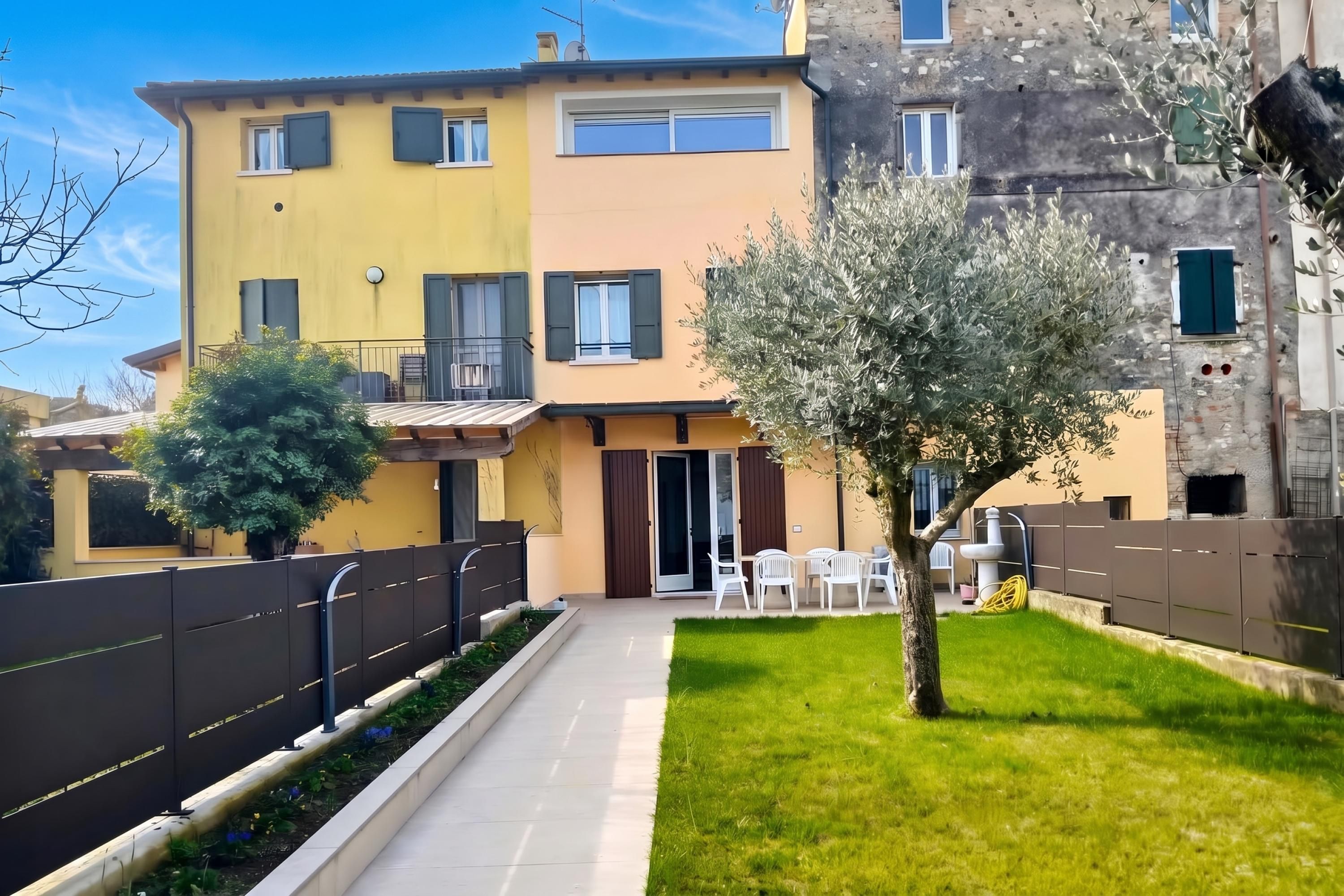 Ein zweistöckiges Wohngebäude mit Balkon, kleinem Garten und gepflastertem Weg.