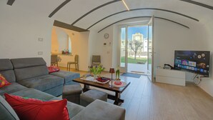 A modern living room with a sofa, coffee table, and TV. - Peschiera few steps from the lake Garden, Terrace, & AC, Peschiera del Garda, Italy (Peschiera del Garda)
