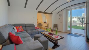 A modern living room with a grey sofa, a coffee table, and a dining area in the background. - Peschiera few steps from the lake Garden, Terrace, & AC, Peschiera del Garda, Italy (Peschiera del Garda)