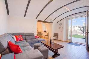 A modern living room with a grey sectional sofa, a wooden coffee table, and a dining area in the background. - Peschiera few steps from the lake Garden, Terrace, & AC, Peschiera del Garda, Italy (Peschiera del Garda)