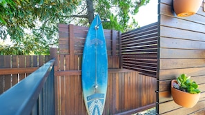 A wooden fence with a surfboard leaning against it.