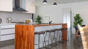 A modern kitchen with a wooden island, bar stools, and pendant lighting.