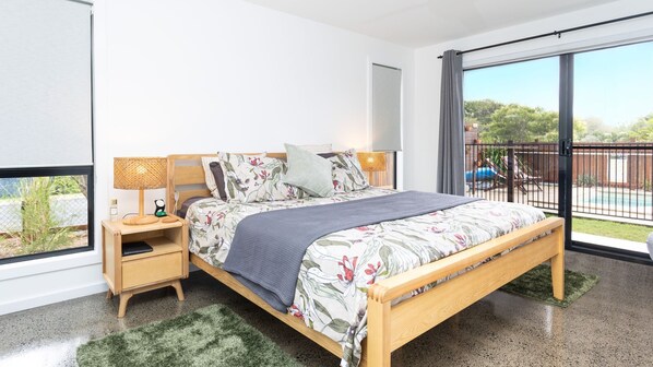 Une chambre avec un lit, une table de chevet et une vue sur une piscine.