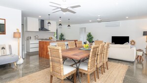 A modern kitchen with white cabinets, a wooden island, and a dining area with wicker chairs and a wooden table.