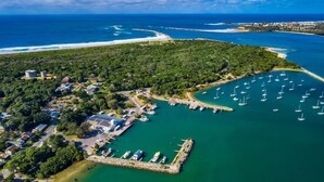 An aerial view of a coastal area with a marina, boats, and a residential area with houses and a solar panel building.