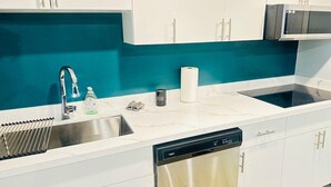 A modern kitchen with white cabinets, a teal backsplash, stainless steel appliances, and a dishwasher. - Modern Private Suite with 100 inch TV Quiet Oshawa (Oshawa)