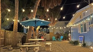 Eine Außenpatio-Terrasse mit Lichterketten, einem blauen Sonnenschirm und Gartenmöbeln.