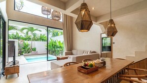 Ein modernes Wohnzimmer mit Pool, einem Essbereich mit Holztisch und -stühlen sowie einem großen Fenster mit Blick auf Grünflächen.