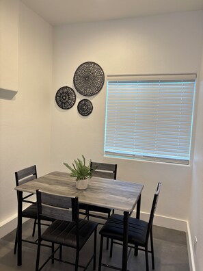 A dining area with a table, chairs, a potted plant, and decorative wall art. - Relax and recharge private studio in Indio, CA (Indio)