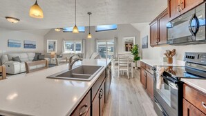 Een moderne keuken met een groot schiereiland, inbouwapparatuur en een eethoek met uitzicht.