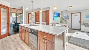 Een moderne keuken met een centraal eiland, houten kastjes en hanglampen.