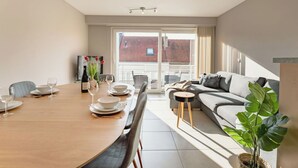En moderne stue med spiseområde, sofa og fjernsyn.