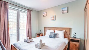 En pænt redt seng med puder, et trægavl og et natbord med en lampe.
