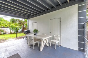 An outdoor patio with a white table and chairs, a grill, and a covered area with a ceiling. - Cozy 4BR Family Retreat Near Parks, Beaches & Malls (North Miami Beach)