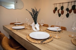 Une table à manger dressée avec des assiettes, des couverts et un vase décoré de feuillage.