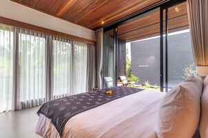 A modern bedroom with a large bed, a view of the outdoors, and a wooden ceiling.