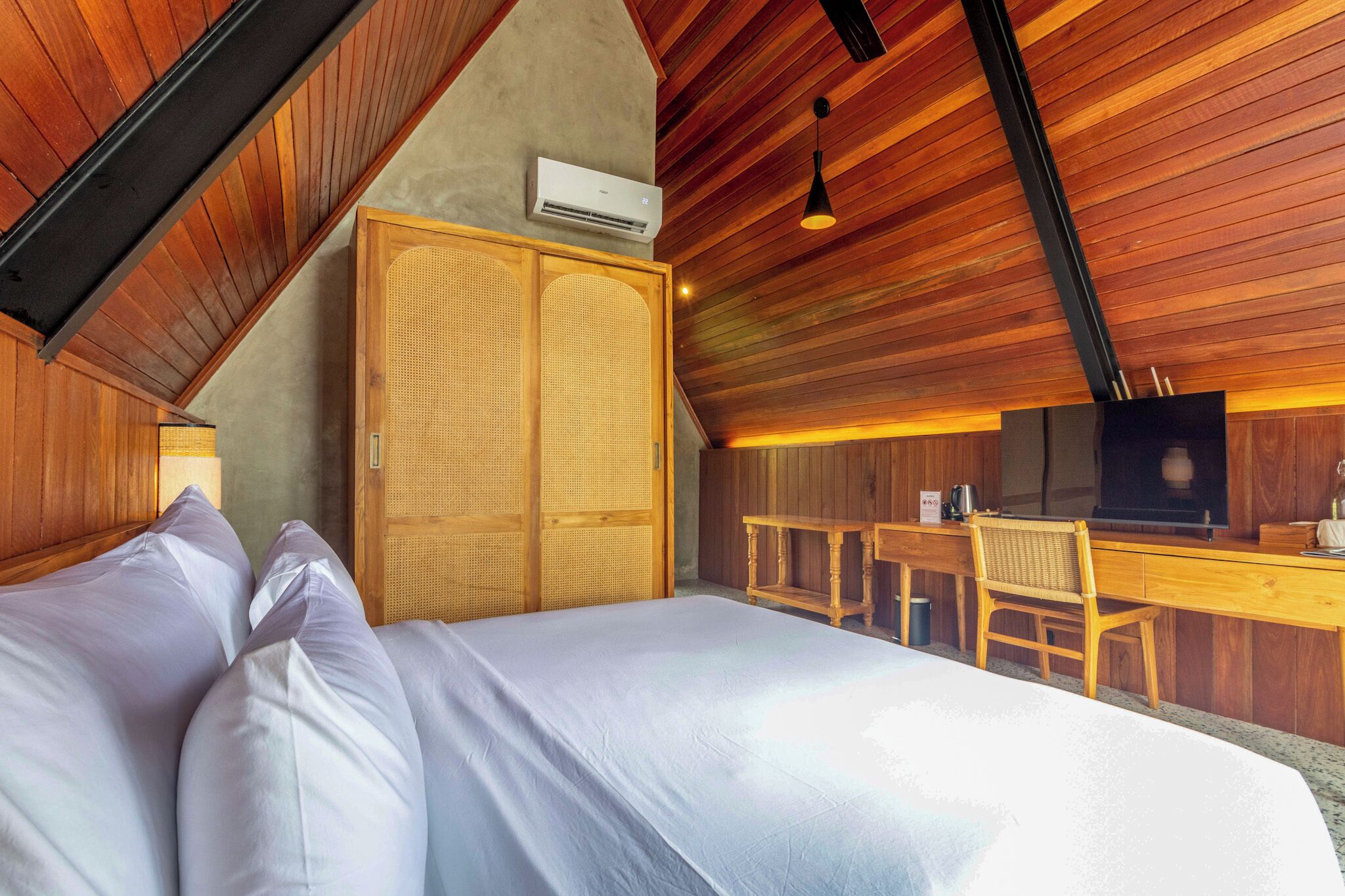 Une chambre à coucher comprenant un lit, un bureau, une chaise, un téléviseur et un appareil de climatisation.