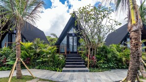 A modern building with a glass entrance, surrounded by tropical plants and stone pathways. - Anandinii Resort Sidemen by AGATA (Sidemen)