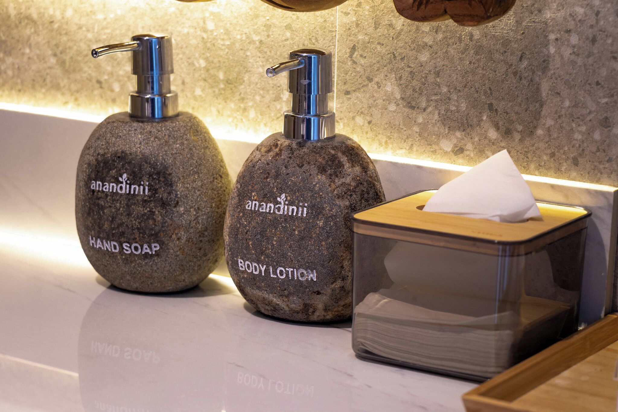 Two stone dispensers labeled 'hand soap' and 'body lotion' with a tissue box beside them.