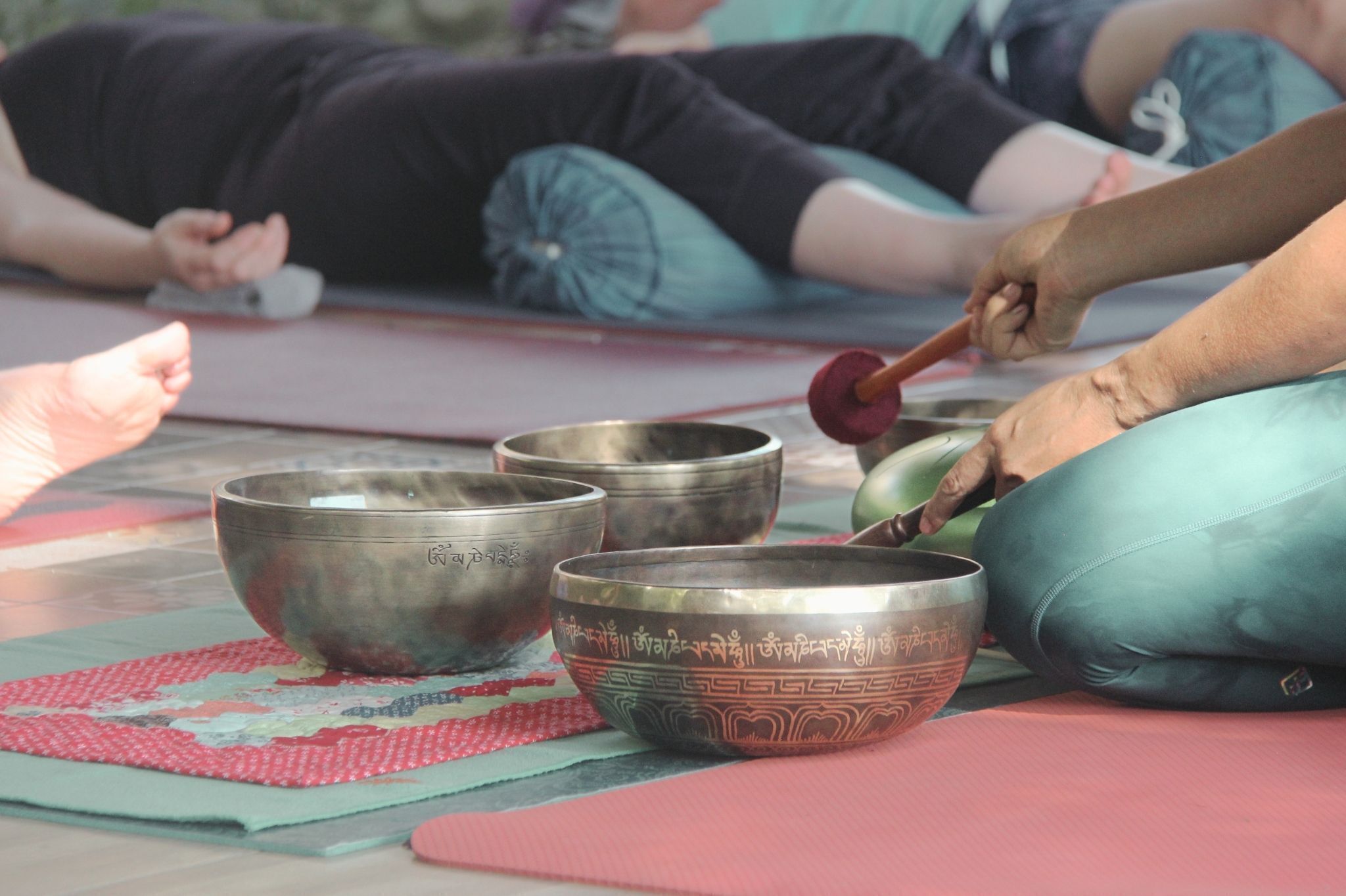 Un grupo de personas meditando sobre una esterilla con cuencos cantores.
