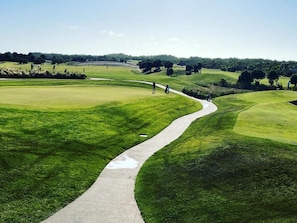 A golf course with a winding path, lush green grass, and distant trees. - Spacious 2-Bed Townhouse Near Torquay Beach (Torquay)