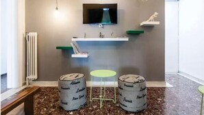 A bathroom with a modern design, featuring a built-in sink, a mirror, and a television above it. There are two stools and a small table in the space. - Athens SmArt Three-Room Apartment (Athens)