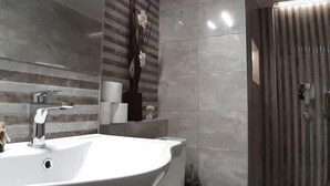 A bathroom with a white sink, a mirror, a towel dispenser, and a shower area. - Athens SmArt Three-Room Apartment (Athens)