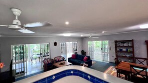 Ein großzügiger Wohnbereich mit Deckenventilator, Billardtisch, Sofa und Esstisch.