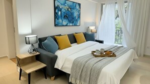 Una habitación de hotel moderna con una cama grande, una mesita de noche, una lámpara, un cuadro y una ventana con cortinas.