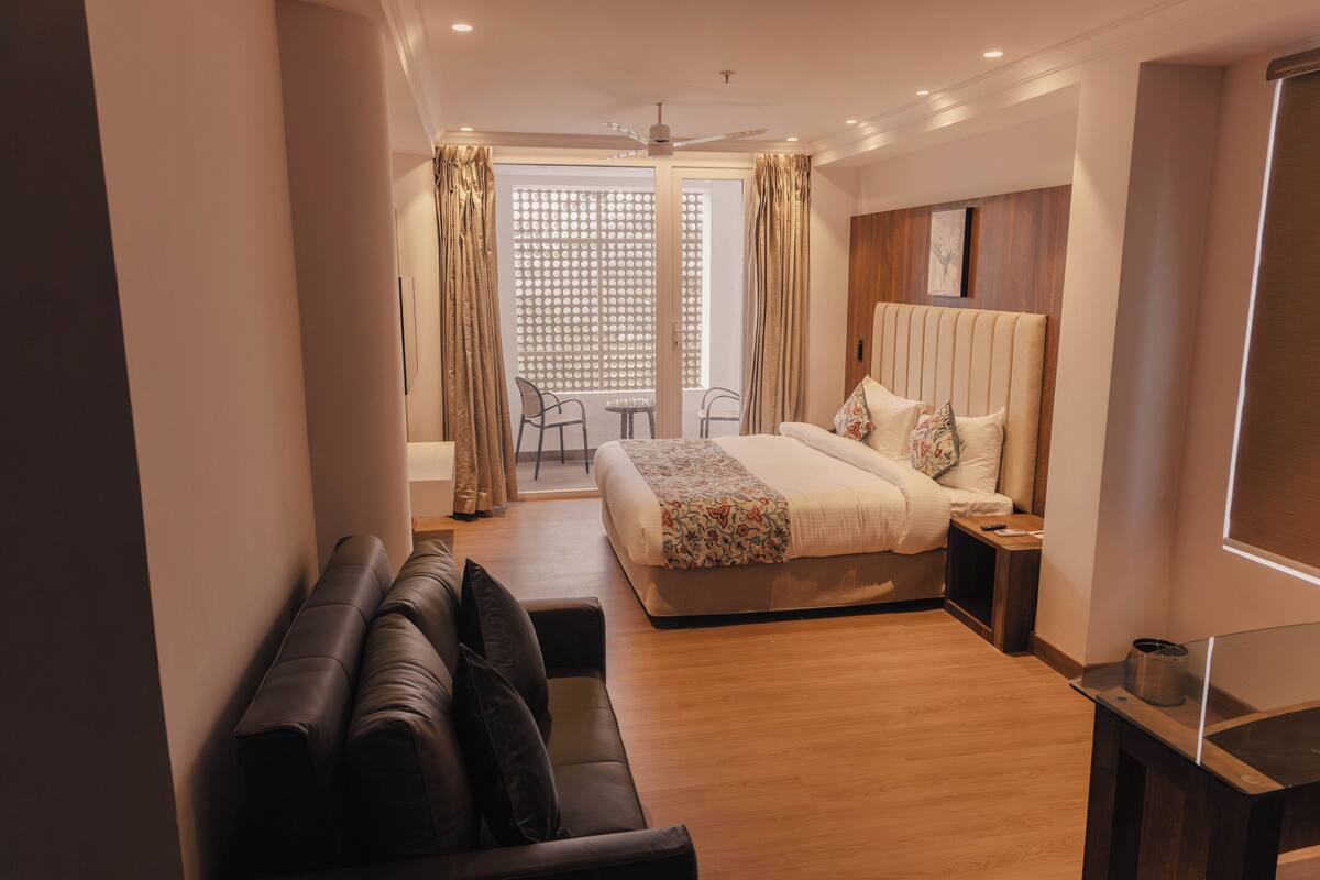 Ein modernes Hotelzimmer mit Bett, einer Sitzecke, einem Balkon und einem Deckenventilator.