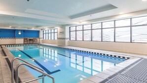 Una piscina interior amb un videt de quadrícula, un rellotge i una finestra amb vista a un pont.