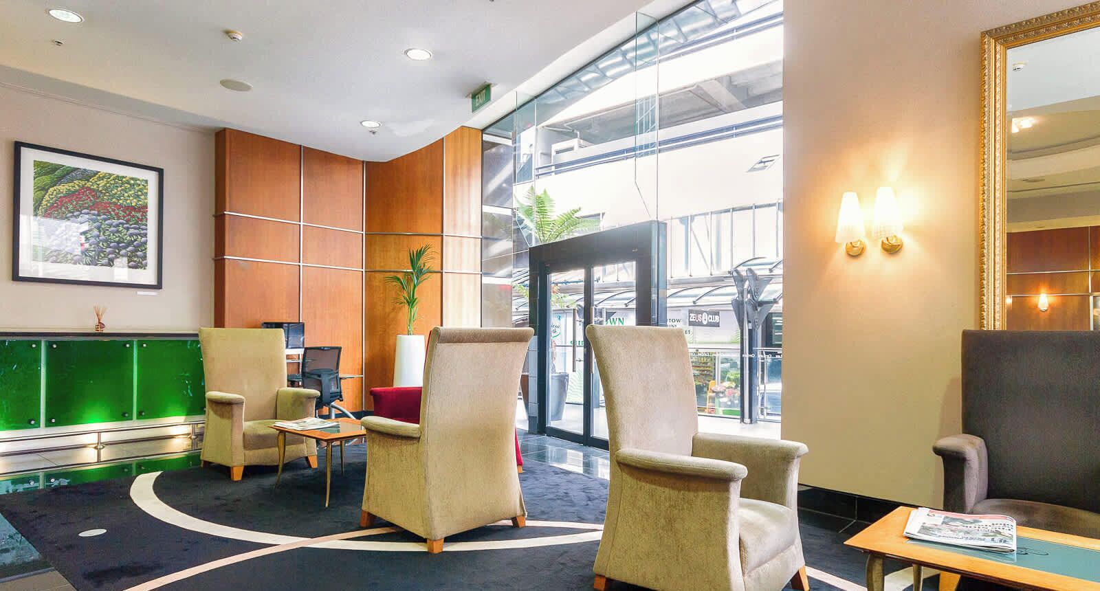 A lobby with seating, a reception desk, a large window, and a framed picture on the wall.