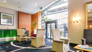 Un vestíbul amb seients, una taquilla d'informació, un finestral gran i un quadre encimbellat a la paret.