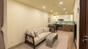 A living room with a sofa, a bench, a dining area, and a kitchen in the background. - Weal Apartment (Da Nang)