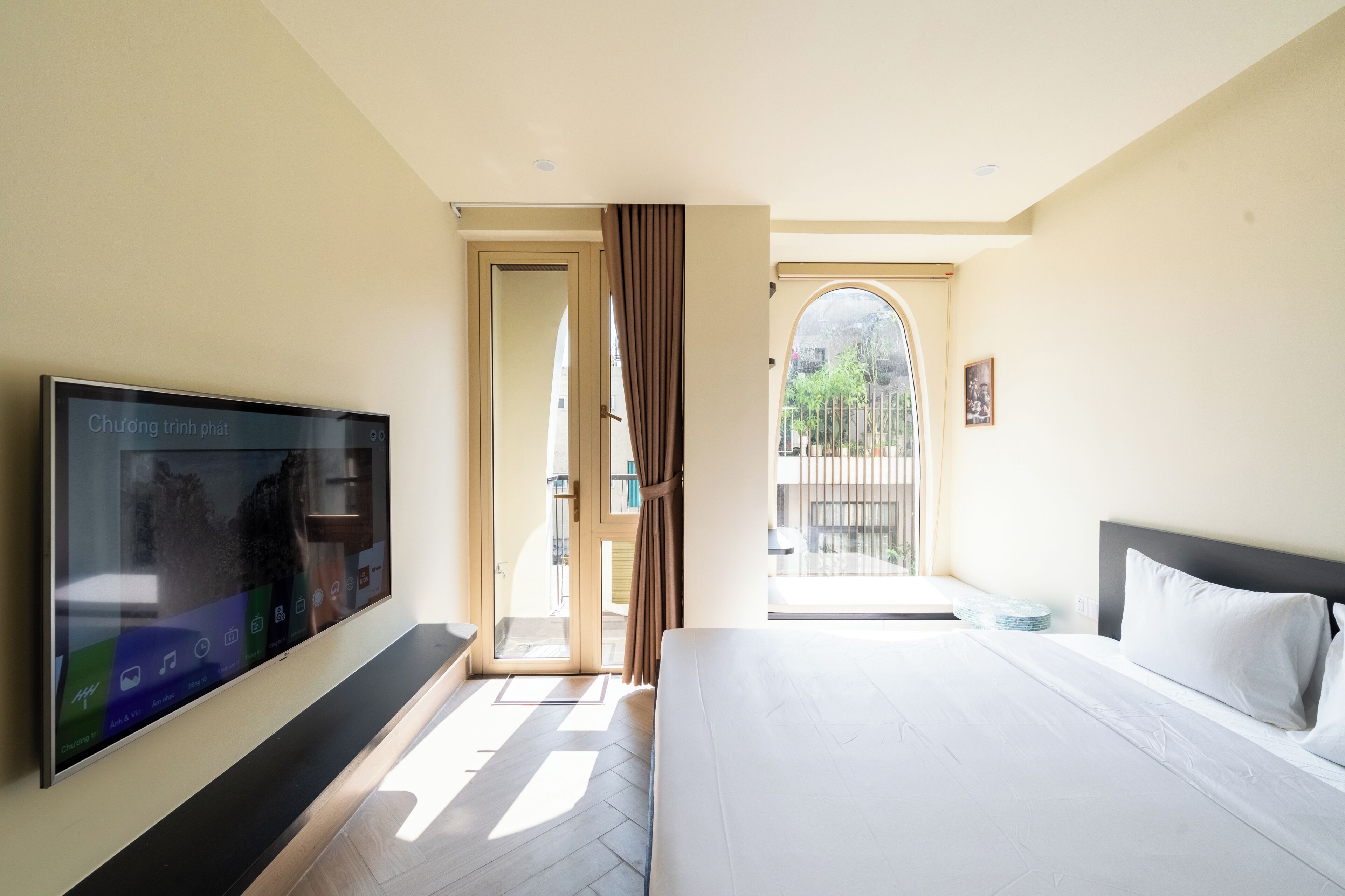 Habitación de hotel con cama, televisión, balcón con vistas y puerta que da al exterior.