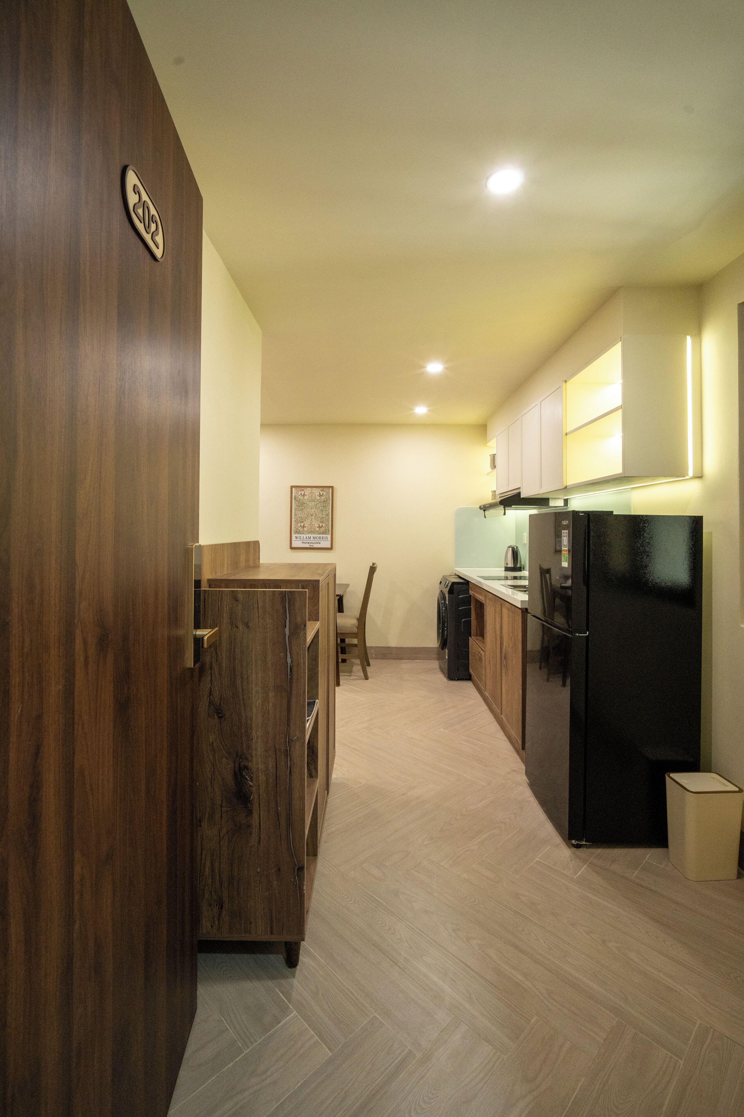 Una cocina moderna con armarios de madera, un refrigerador negro y una zona de comedor con mesa y sillas.