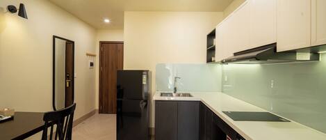 A compact kitchen with a refrigerator, dishwasher, and a small island with a sink.