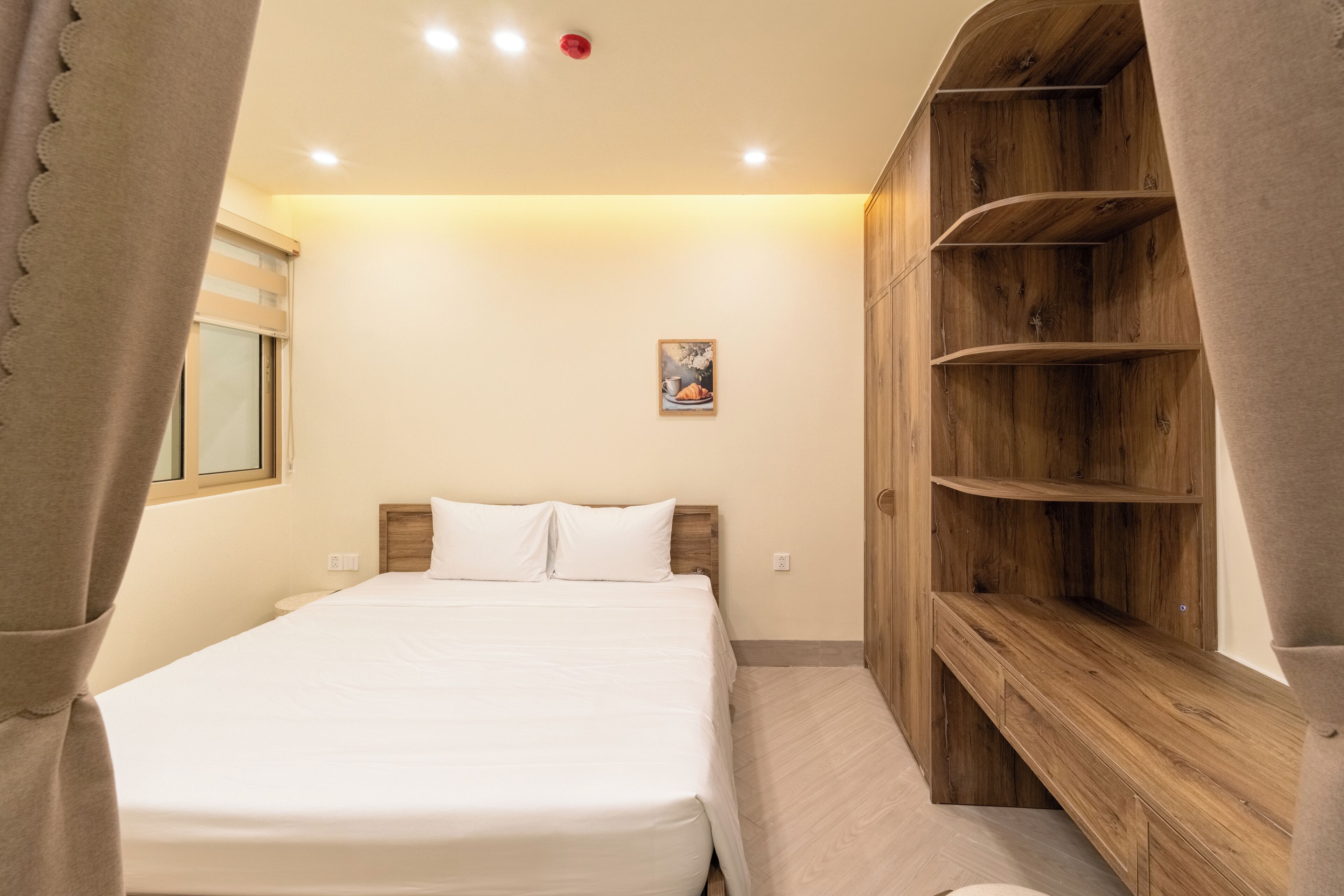 A bedroom with a bed, a wooden shelf unit, a window with blinds, and a small picture on the wall.