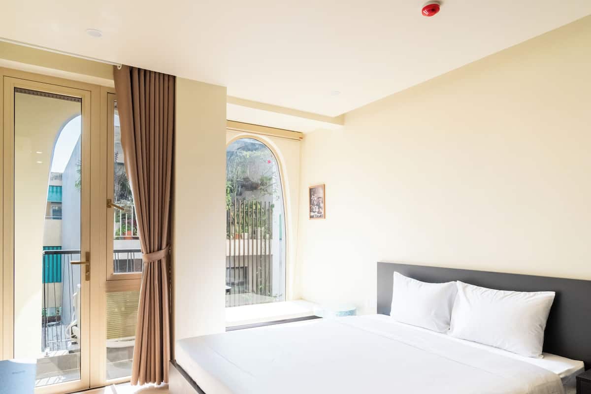 A bedroom with a bed, a window, and a door leading to an outdoor area.