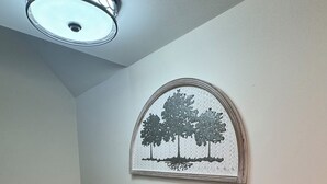 A room with a carpeted floor, a ceiling light fixture, a wall-mounted picture of trees, and a power outlet. - Cozy 3-bedroom house in delightful Superiorwith a Riverview (Superior)