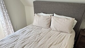 A bed with a grey upholstered headboard, a white textured bedspread, and two pillows. - Cozy 3-bedroom house in delightful Superiorwith a Riverview (Superior)
