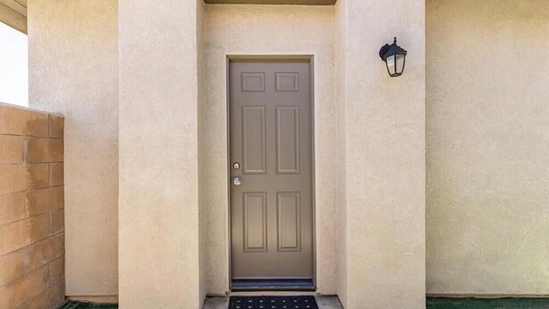 A beige door with a metal handle, a small step leading up to it, and a wall-mounted light fixture to the right. - Serene casita with AC in beautiful Coachella perfect for getaway (Coachella)