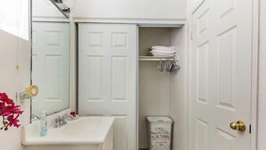 A bathroom with a sink, mirror, toilet, and a laundry basket. - Serene casita with AC in beautiful Coachella perfect for getaway (Coachella)