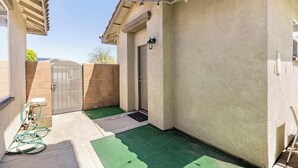 A small, enclosed patio area with a door, a hose, and a green mat. - Serene casita with AC in beautiful Coachella perfect for getaway (Coachella)